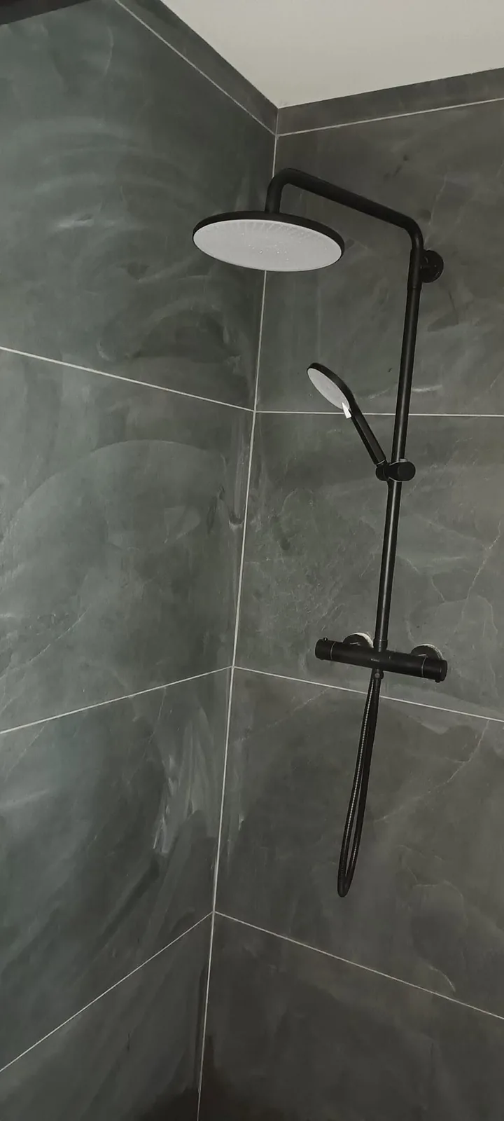 Black rainfall shower fitted in a slate tiled bathroom